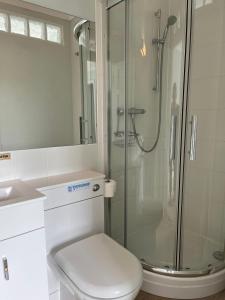 a white bathroom with a shower and a toilet at Westley B&B in Uplyme