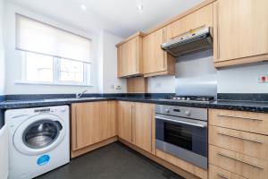 a kitchen with wooden cabinets and a washer and dryer at Bright 2 BDR house wgarden & parking, Greenwich in London