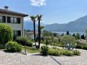 a house with palm trees and a view of the water at Residenza Margherita in Tremezzo