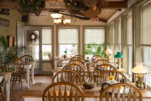 a dining room with tables and chairs and windows at 1825 Inn Bed and Breakfast in Palmyra