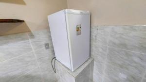 un frigorifero bianco nell'angolo di una stanza di Hospedaria e Alojamento SítioChaminé Piscinas Naturais a Itaguaí