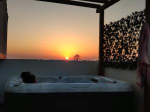 uma pessoa numa banheira com um pôr-do-sol ao fundo em Apartamento da Praia com jacuzzi em Portimão