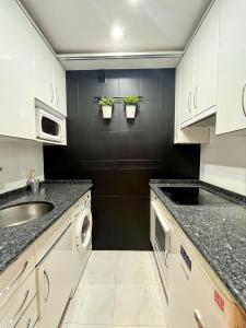 una cocina con armarios blancos y fregadero en Agradable Apartamento en el Centro de Burgos Parking Free ATUAIRE, en Burgos