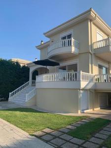 a large white house with a balcony and an umbrella at Villa Zose' luz in Káto Ássos