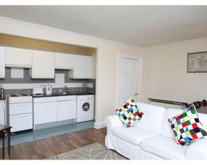 a living room with a white couch and a kitchen at Glasgow City Apartments in Glasgow