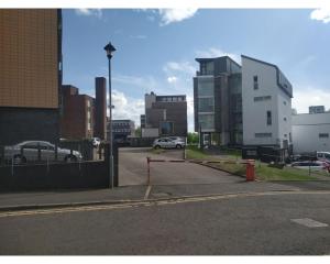 a city street with a parking lot and buildings at Glasgow City Apartments in Glasgow
