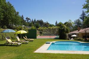 uma piscina com cadeiras e guarda-sóis ao lado de uma casa em Casa das Camélias em Guimarães