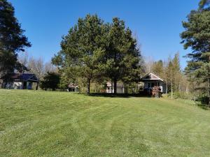 a large grassy field with a house in the background at Līdumnieki in Vērgale