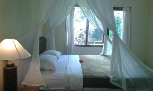 1 dormitorio con cama con dosel y ventana en Gangga House, en Ubud