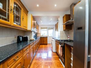 a kitchen with wooden cabinets and black counter tops at Pass the Keys Beautiful Wembley Entire House in London