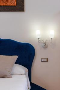 a bed with a blue headboard and a light on a wall at Lovely Rooms - Guest House Suites in Triggiano