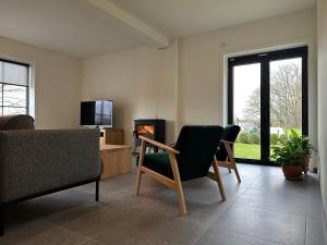 sala de estar con sofá, sillas y chimenea en De Bovenbuur en Lummen