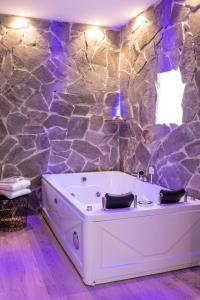 La salle de bains est pourvue d'une baignoire dans un mur en pierre. dans l'établissement Lovely Rooms - Guest House Suites, à Triggiano