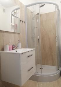a white bathroom with a shower and a sink at Apartament na ul. Olsztyńskiej in Giżycko