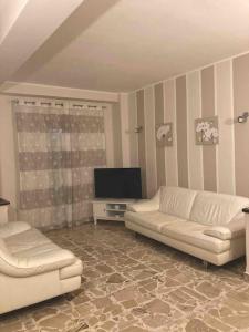 a living room with two white couches and a flat screen tv at Appartamento via Roma in Siculiana