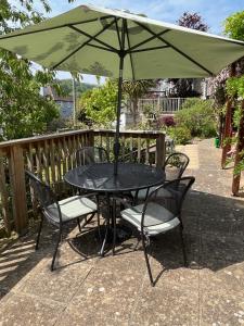 a table and chairs with an umbrella on a patio at Westley B&B in Uplyme