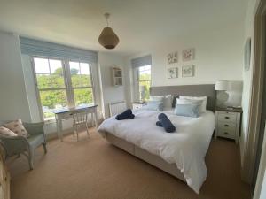 a bedroom with a large white bed with blue pillows at Westray House in Polzeath