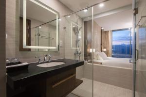 a bathroom with a sink and a shower and a bed at Panorama Apartment Nha Trang in Nha Trang