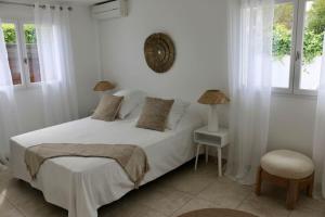 een witte slaapkamer met een bed en een stoel bij Maison idéale à 3min de la plage in Mandelieu-la-Napoule