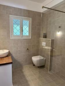 łazienka z toaletą, umywalką i oknem w obiekcie Casa Bruno w mieście Sivota