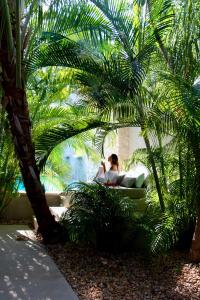 a woman sitting in a bath tub under a palm tree at The Diplomat Boutique Hotel in Mérida +144 photos