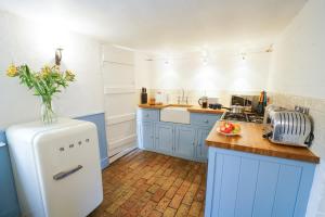 オールドバラにあるAldeburgh Cottageのキッチン(青いキャビネット、白い冷蔵庫付)