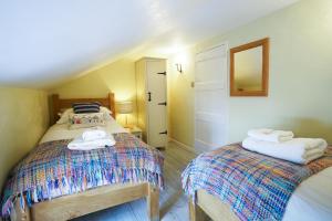 a bedroom with two beds and a mirror on the wall at Aldeburgh Cottage in Aldeburgh