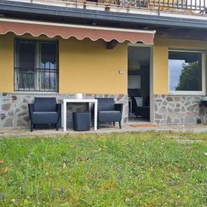 une maison jaune avec deux chaises et une table dans l'établissement Civico 25, Carcioni - Belgirate, à Belgirate