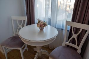 a white table with a vase of flowers on it with two chairs at HY 2 SIBIU in Şelimbăr