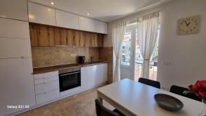 una cucina con armadi bianchi, tavolo e orologio di Apartment Rivarela BLU - newly renovated and top location near sea a Novigrad Istria