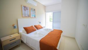 1 dormitorio con cama con sábanas de color naranja y ventana en Residencial Las Salinas en Maresias