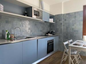 cocina con armarios azules, fregadero y mesa en Ca' Magna Apartment en Venecia