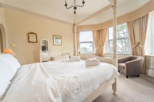 um quarto com uma grande cama branca e uma cadeira em Bourne Hall Country Hotel em Shanklin