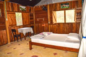 1 dormitorio con cama, mesa y ventanas en Hostal Caño Nevera, en La Macarena