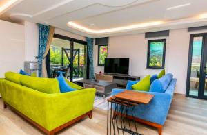 a living room with yellow and blue chairs and a television at House Sapphire in Marmaris