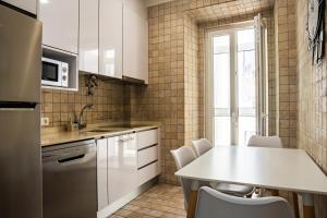 een keuken met witte kasten en een tafel en stoelen bij Casa Ribeiro in Nazaré