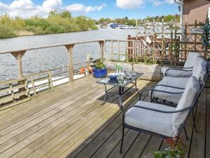 a deck with two chairs and a table next to the water at Evening Glory in Brundall
