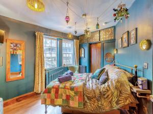 a bedroom with blue walls and a bed with a colorful bedspread at Buttress Retreat in Hebden Bridge