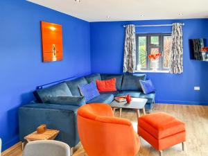 a blue living room with a blue couch and orange chairs at Araglin in Worstead