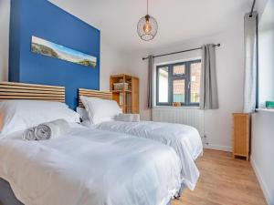 two beds in a bedroom with a blue wall at Araglin in Worstead