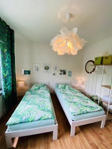 two twin beds in a room with a chandelier at Eifel-House - FeWo in Weilerswist