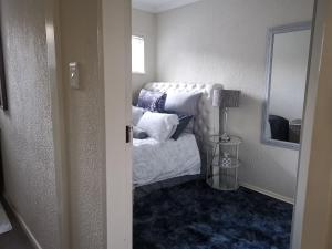 Falklands Guest House في جوهانسبرغ: غرفة نوم بسرير مع مخدات ومصباح