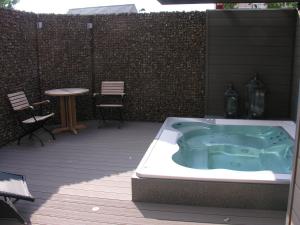 Welldone Resort / Cozy Wine في Nieuwerkerken: يوجد حوض استحمام ساخن على السطح مع طاولة وكراسي