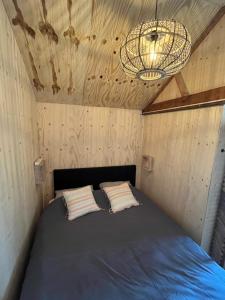 a bed in a small room with a chandelier at Eb en Vloed in Huisduinen