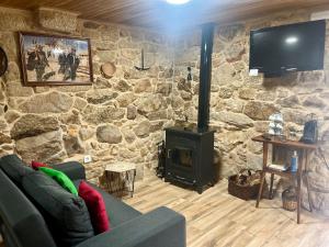 a living room with a stone wall with a fireplace at Casinhas da Capela in Tourém