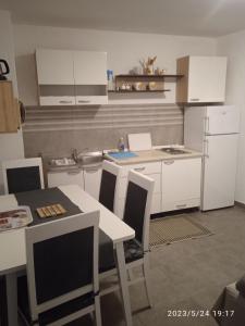 セニにあるApartment Forticaの白いキャビネットとテーブルと椅子のあるキッチン