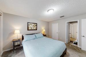 een slaapkamer met een bed met blauwe lakens en 2 lampen bij Urban Oasis in Jacksonville