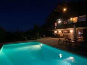 Cabane Jacomeli Genève في Collonges-sous-Salève: مسبح ازرق بالليل مع بيت