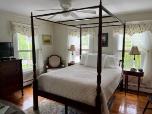 a bedroom with a canopy bed and a television at Bourne Bed and Breakfast in Ogunquit