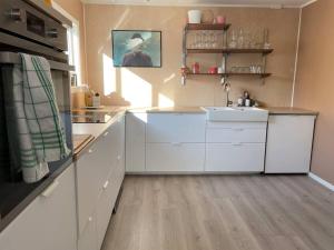 una cocina con armarios blancos y fregadero en House in the center of Andenes en Andenes